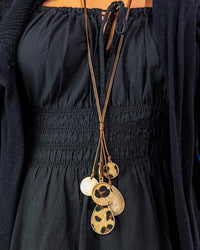 Long necklace with gold and leopard print pendants on a black outfit