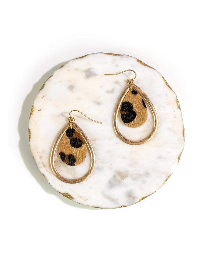 Gold earrings with faux fur black leopard print on a white marble surface