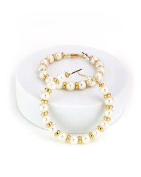 Pearl and gold beaded hoop earrings on a white stand
