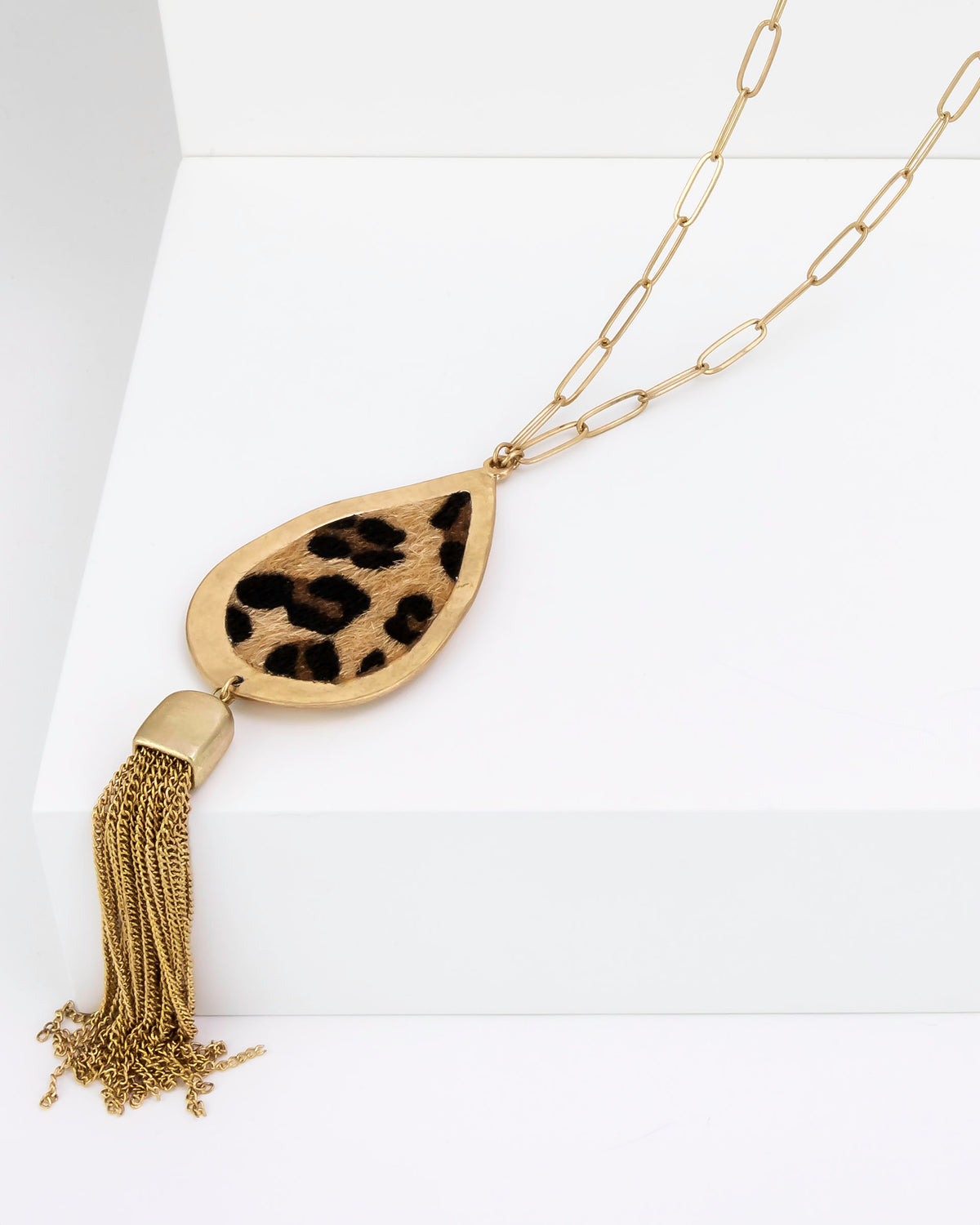Gold necklace with leopard print pendant and tassel on a white background