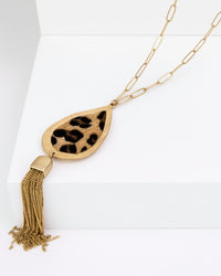 Gold necklace with leopard print pendant and tassel on a white background