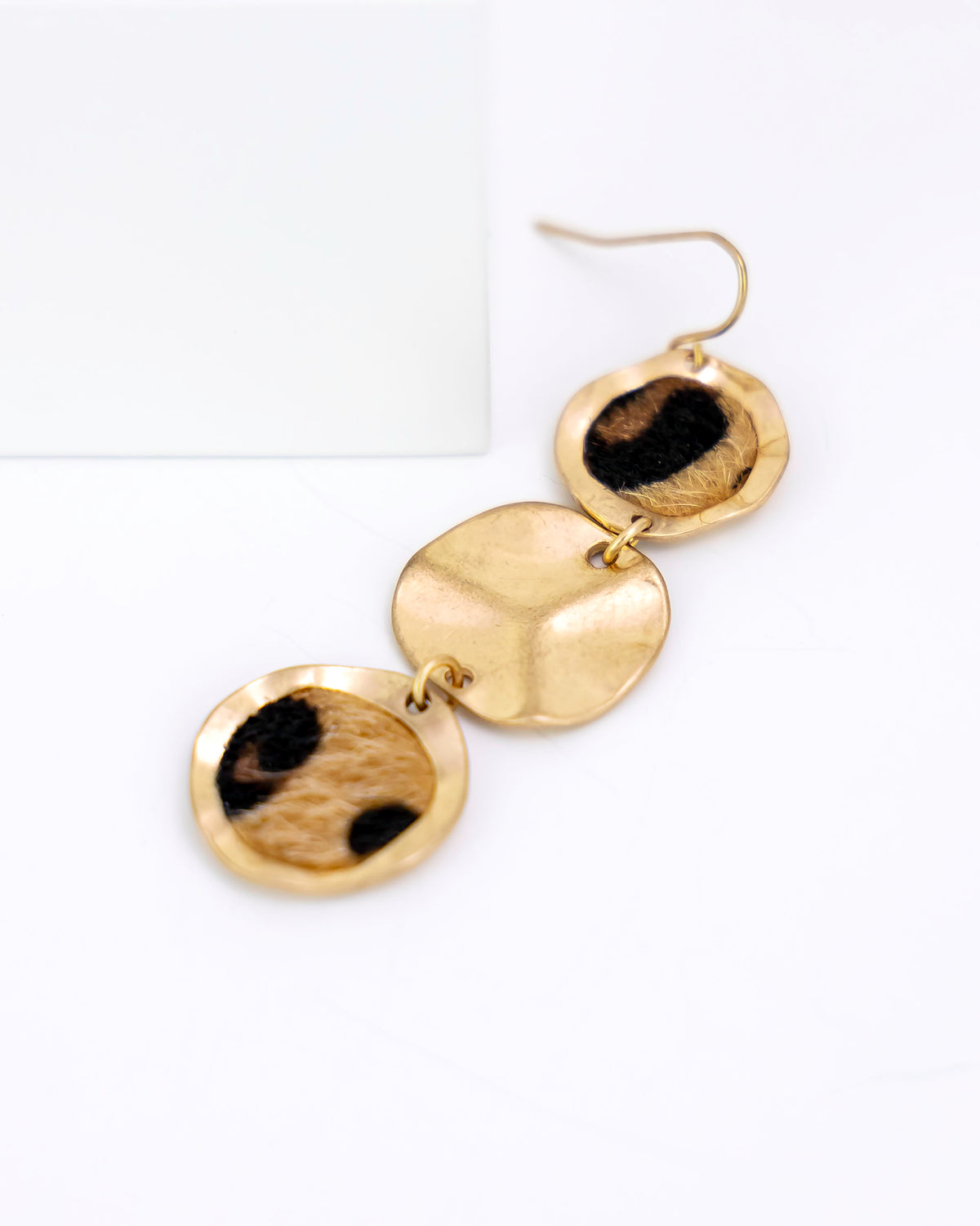 Gold and leopard faux fur earrings on a white background