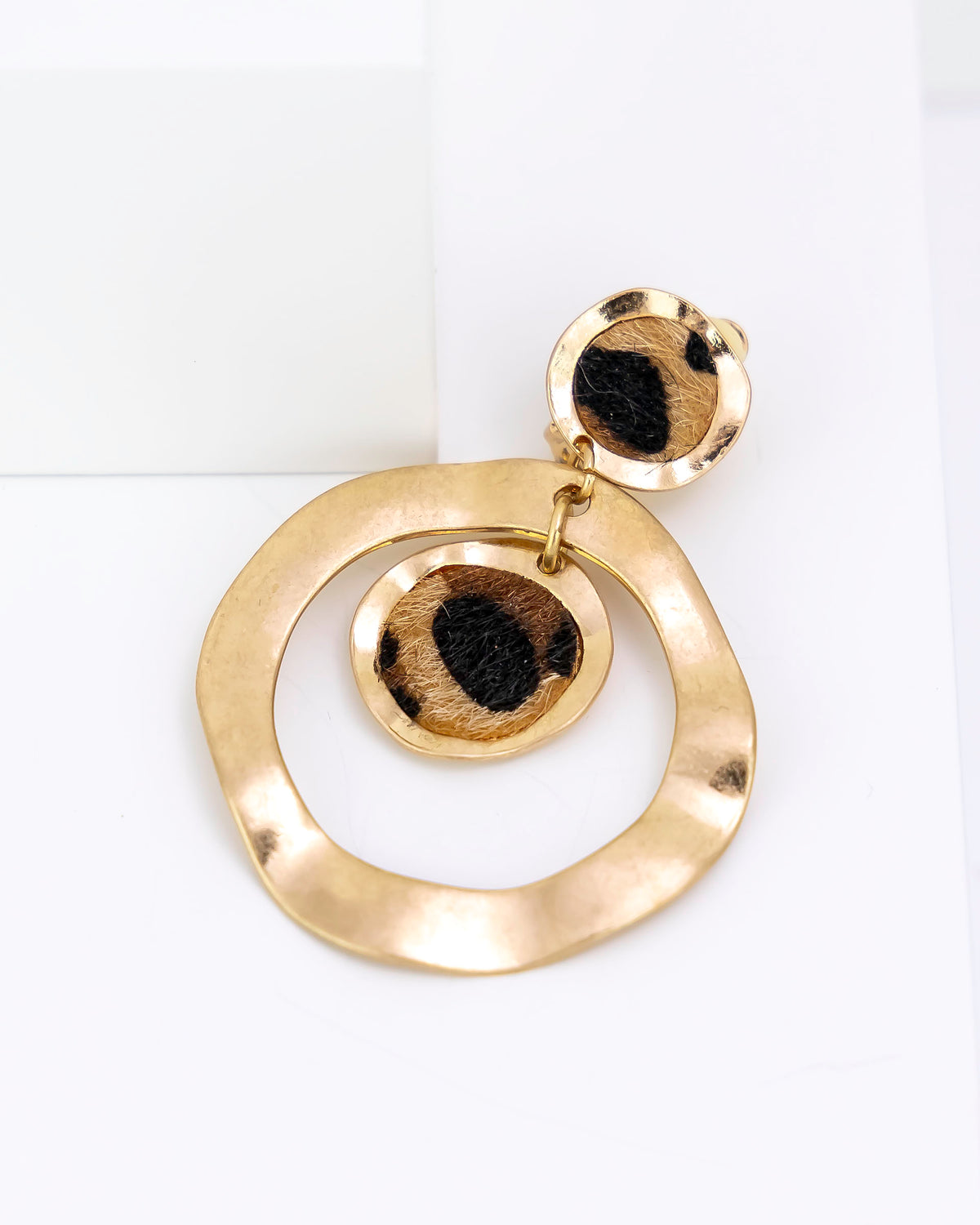Gold circular earring on a white background with leopard faux fur
