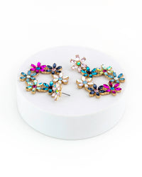 Multicolored gemstone earrings on a white circular stand