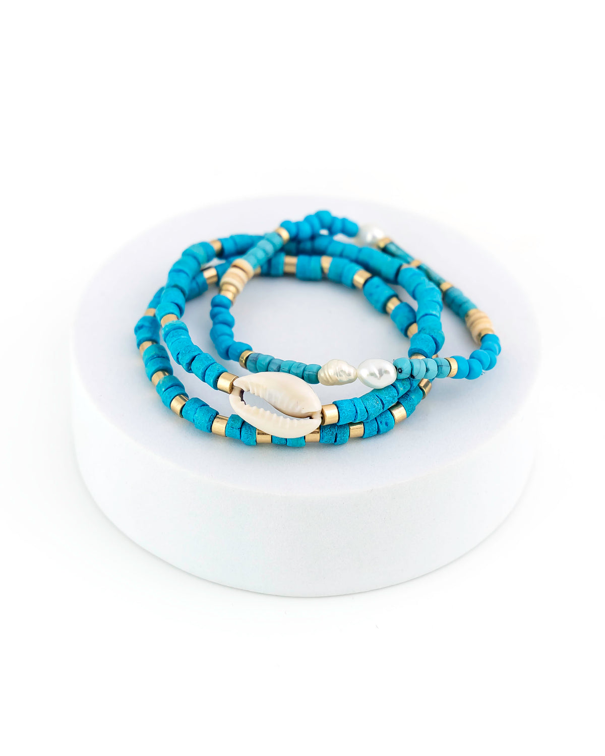 Blue beaded bracelet with shell and gold accents on a white background