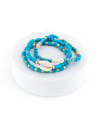 Blue beaded bracelet with shell and gold accents on a white background