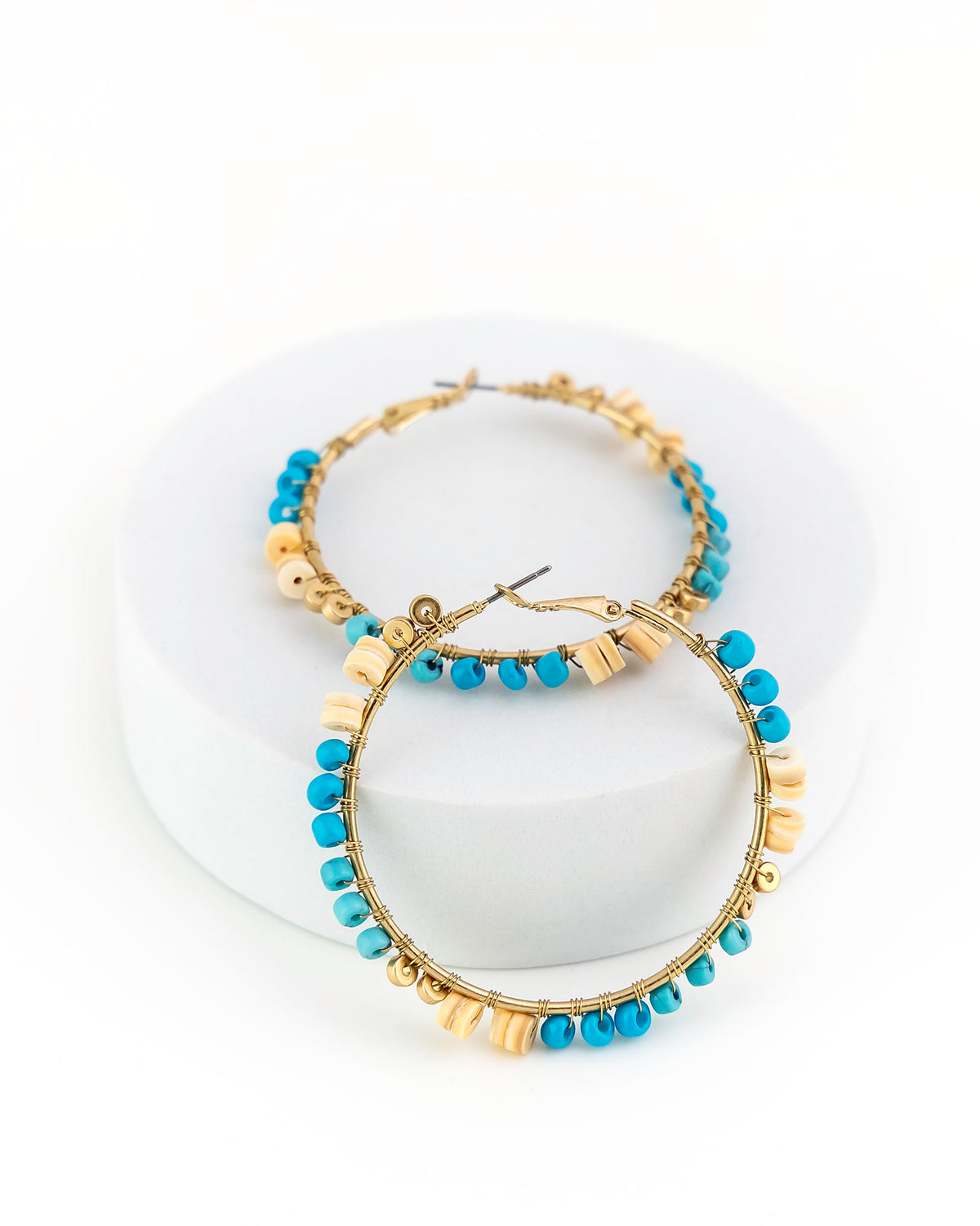Gold hoop earrings with blue beads on a white background