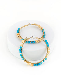 Gold hoop earrings with blue beads on a white background