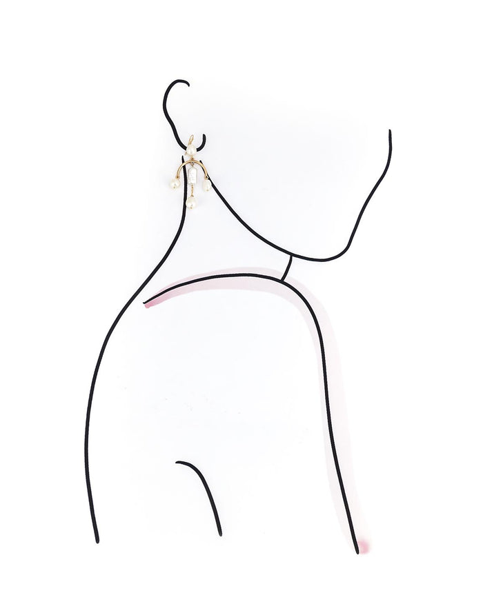 Gold and pearl earrings on a model outline with a white background