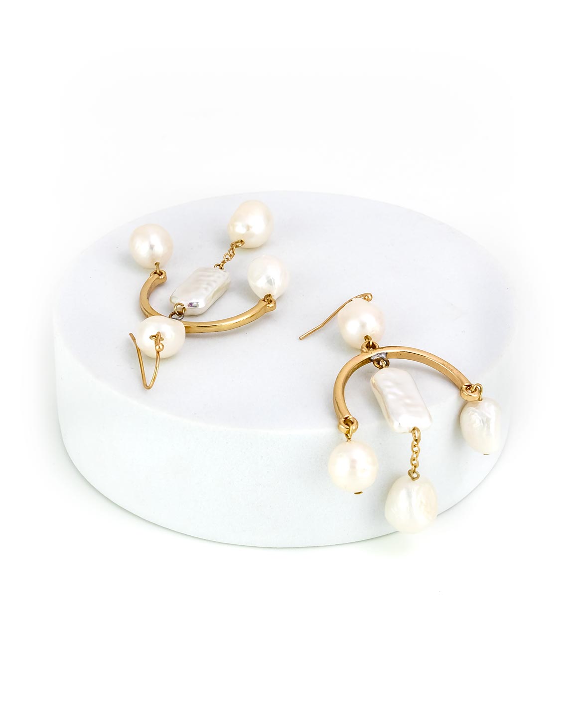 Gold and pearl earrings on a white stand