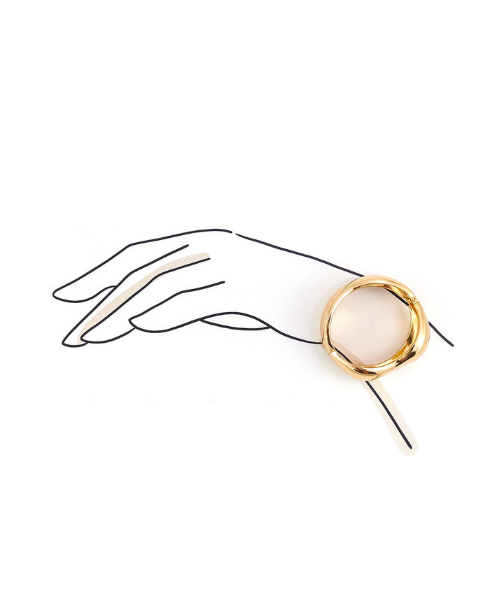 Gold cuff bracelet held by a stylized hand on a white background