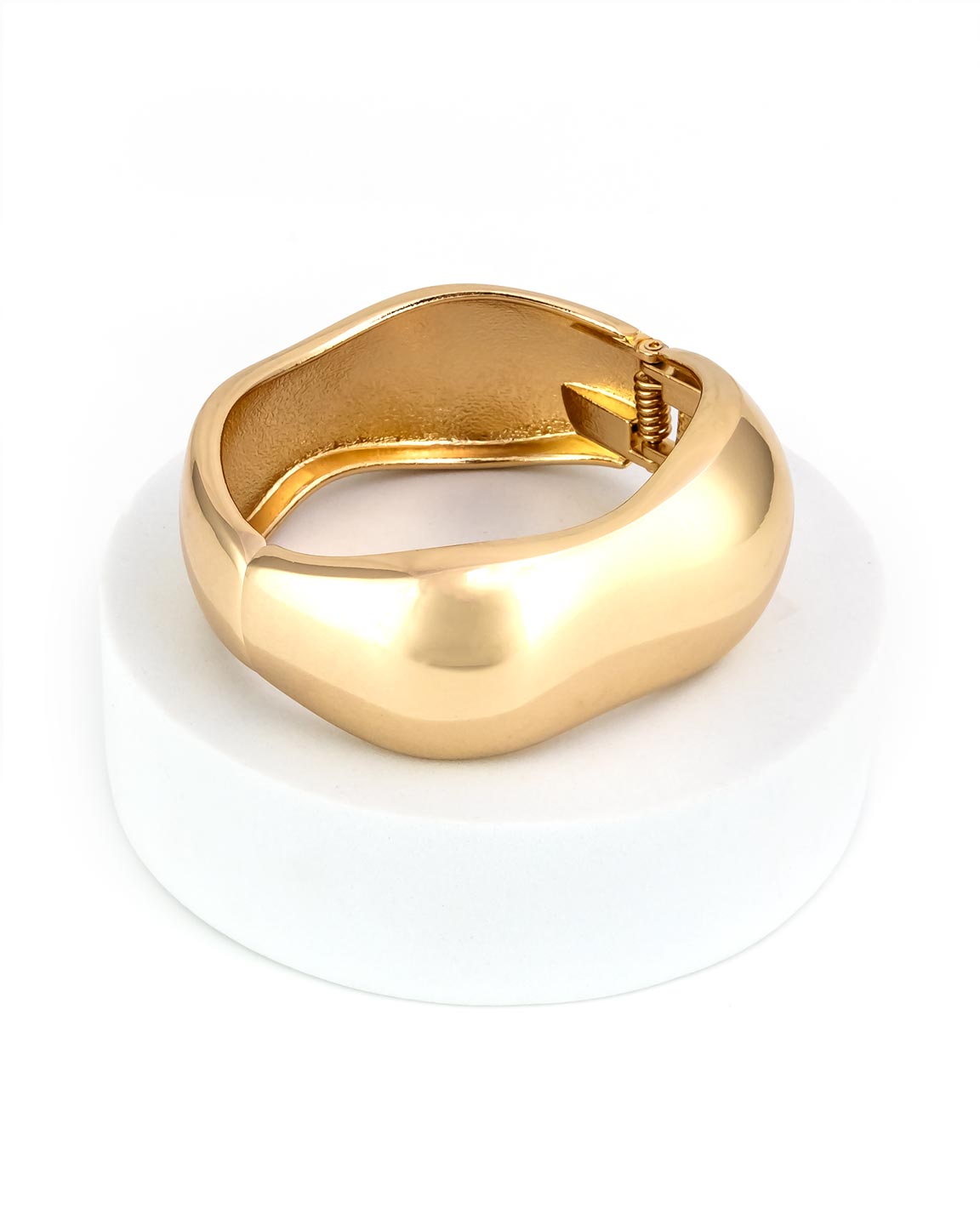 Gold cuff bracelet on a white stand