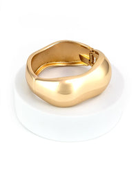 Gold cuff bracelet on a white stand