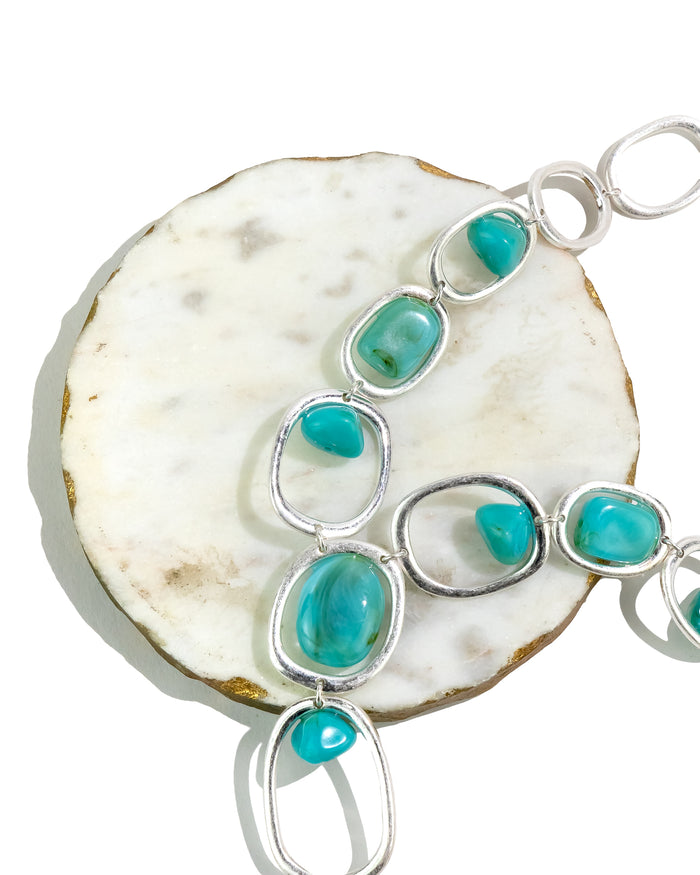Turquoise stone and silver bracelet on a white shell background – Dauplaise Jewelry