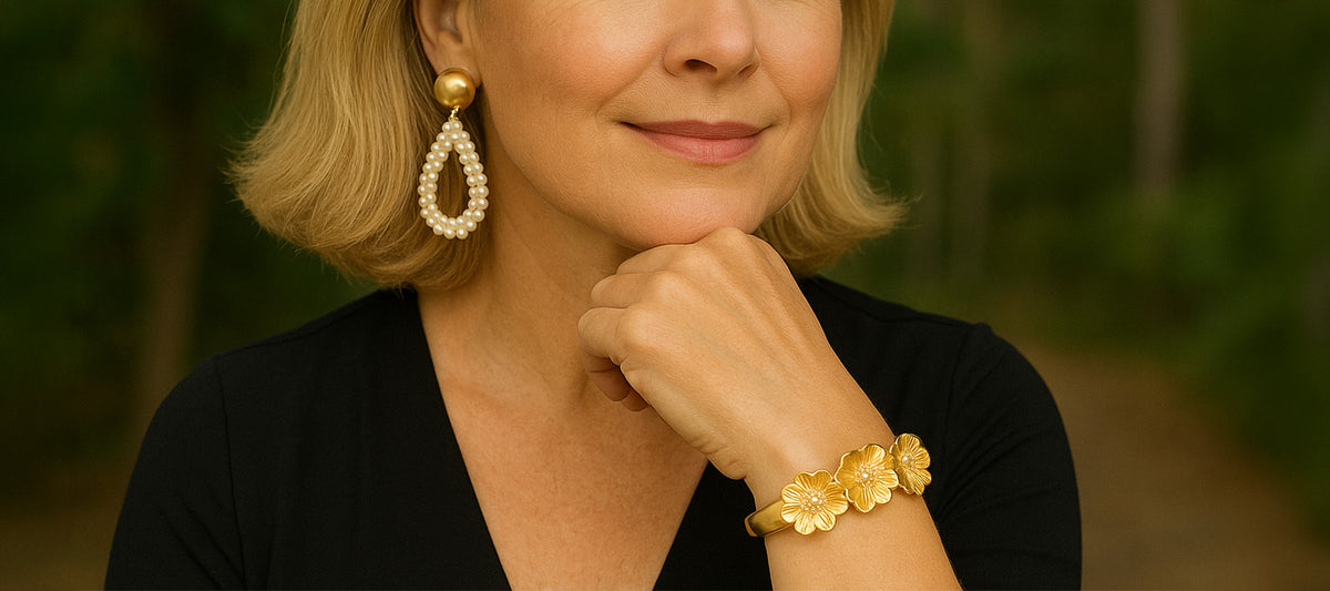 Woman wearing gold earrings and bracelet with a blurred natural background
