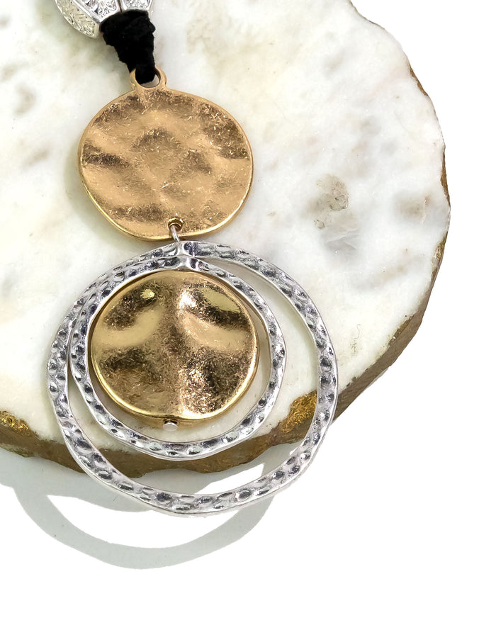 Gold pendant with circular design on a white stone surface