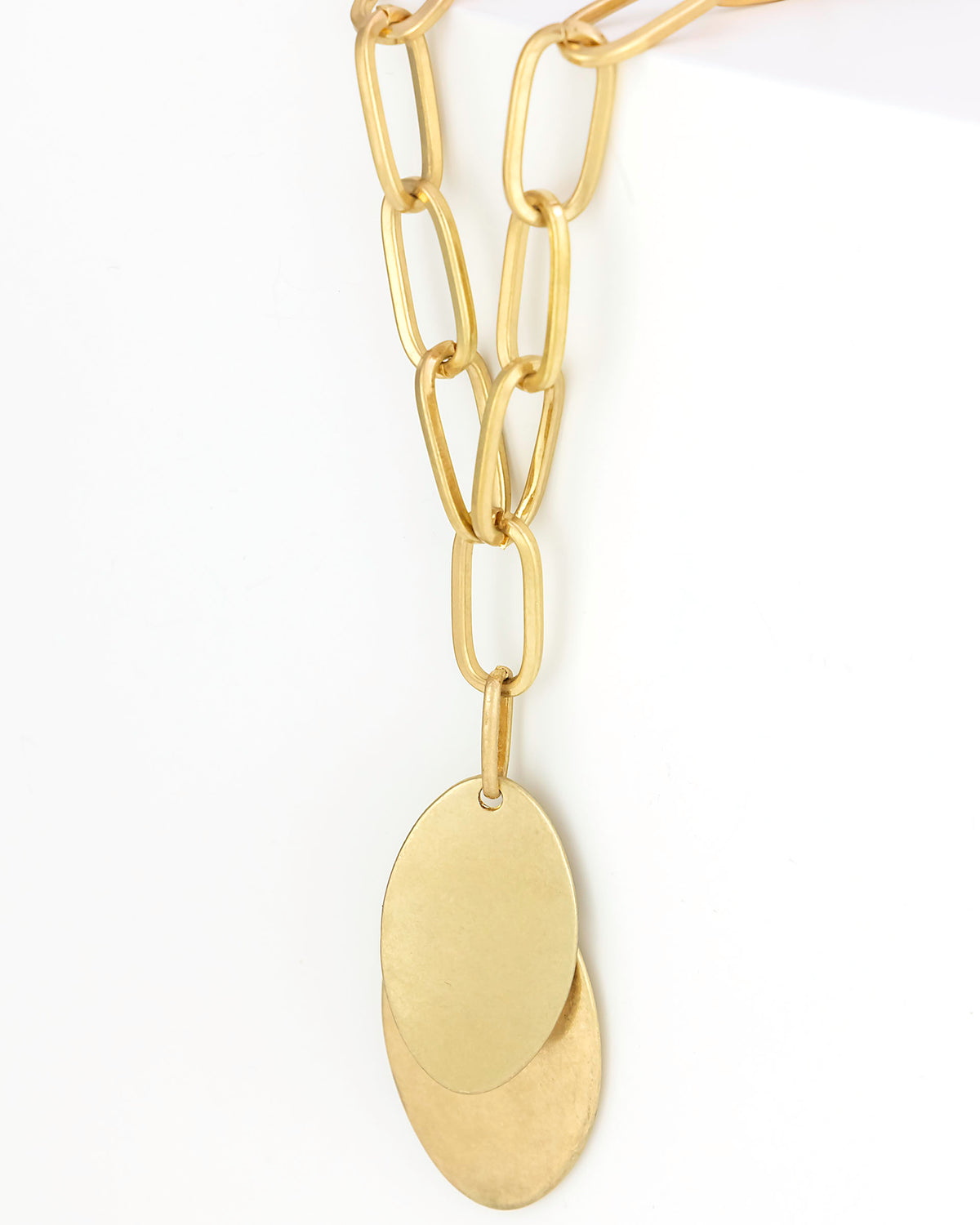 Gold chain necklace with a leaf-shaped pendant on a white background