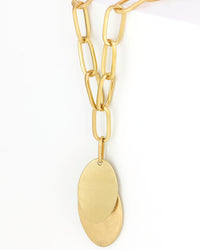 Gold chain necklace with a leaf-shaped pendant on a white background