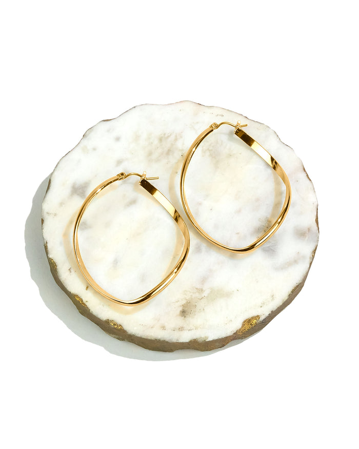 Gold hoop earrings on a white marble surface