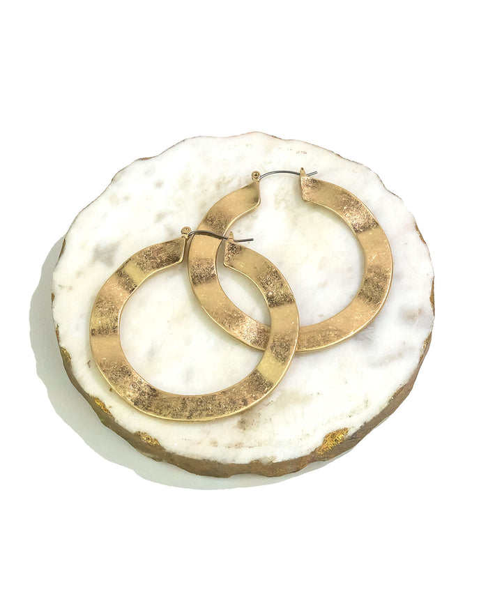 Gold hoop earrings on a white marble surface
