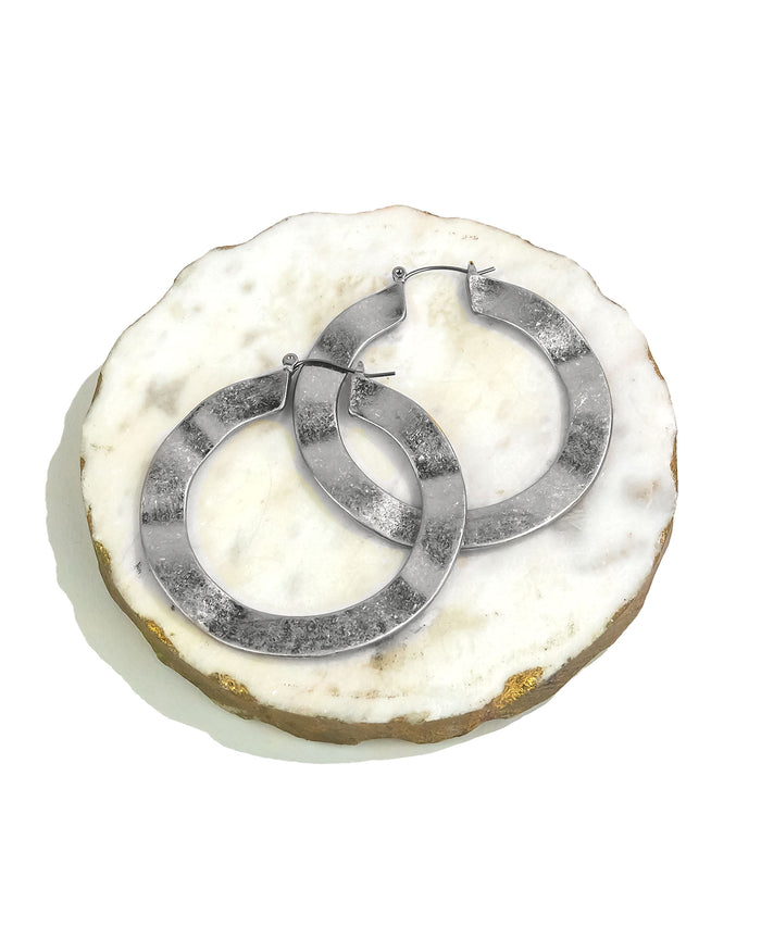 Pair of silver hoop earrings on a textured white surface