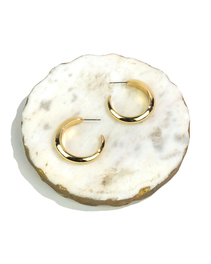 Gold hoop earrings on a marble surface