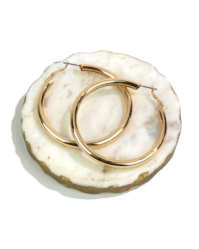 Large gold hoop earrings on a white marble surface