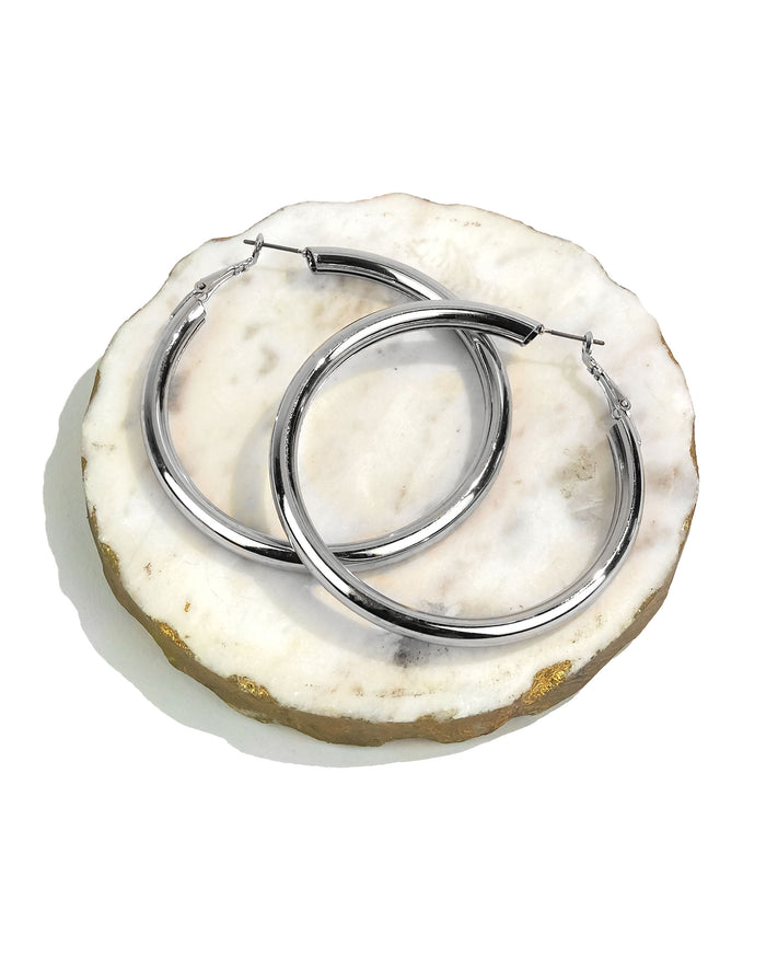 Large silver hoop earrings on a round stone surface