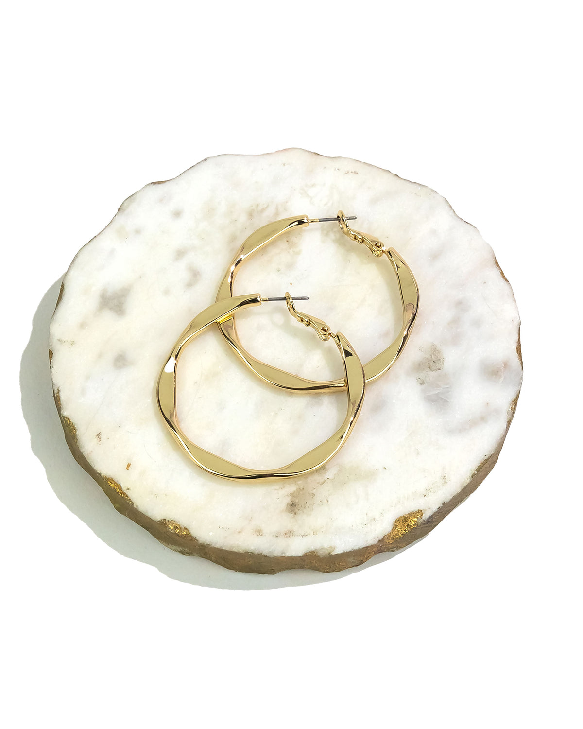Gold hoop earrings on a textured white surface