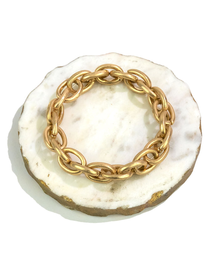 Gold chain bracelet on a white stone surface