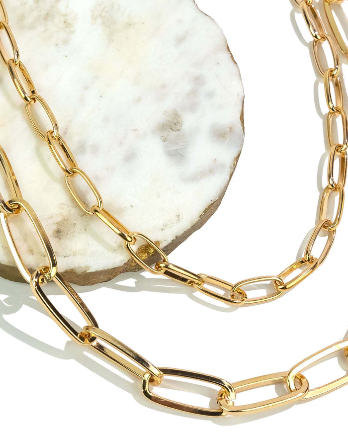Gold chain necklace on a textured white surface