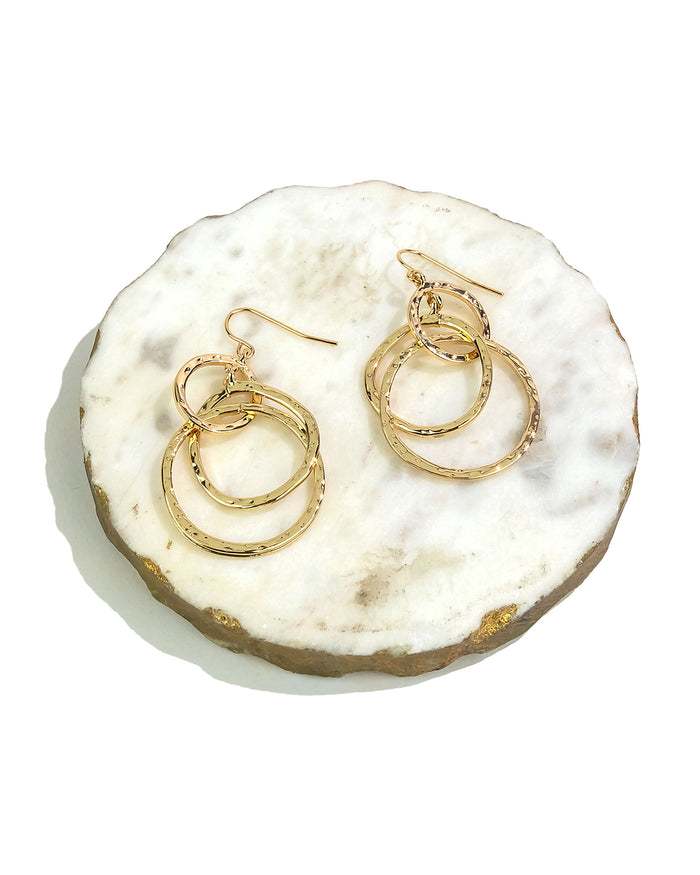Gold hoop earrings on a white stone surface