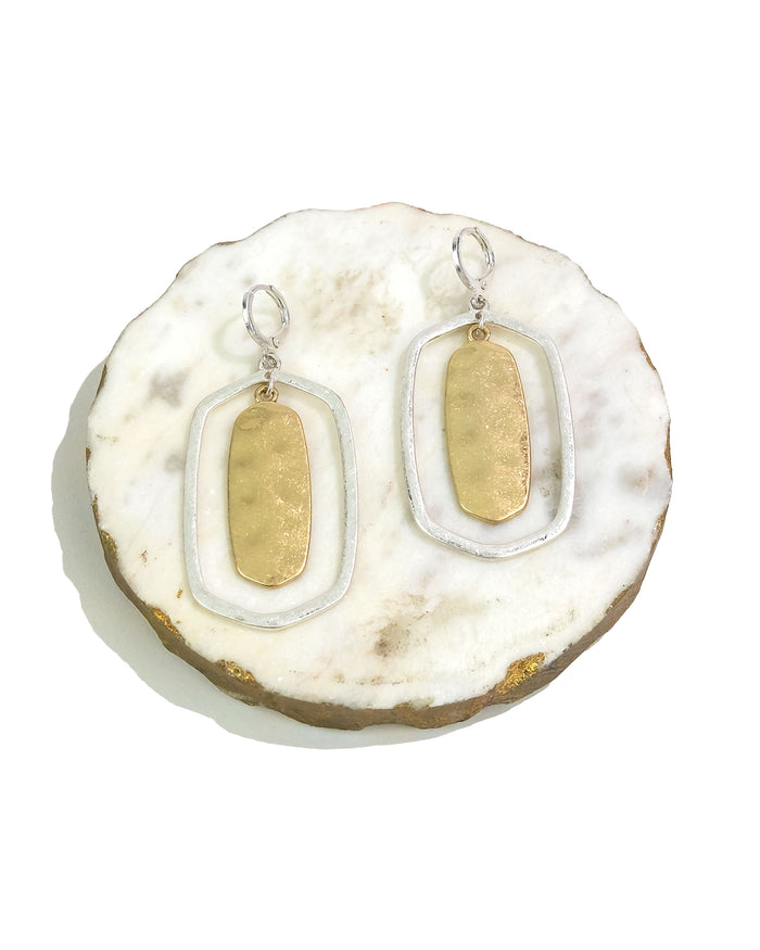 Gold and white earrings on a decorative stone surface