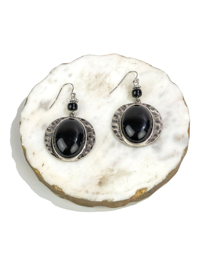 Pair of black stone earrings on a white stone surface