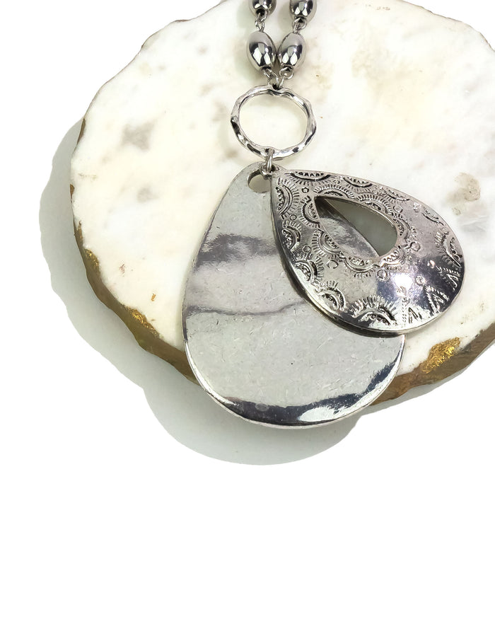 Silver pendant necklace on a white stone surface