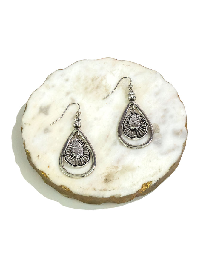 Pair of silver teardrop earrings on a white stone surface