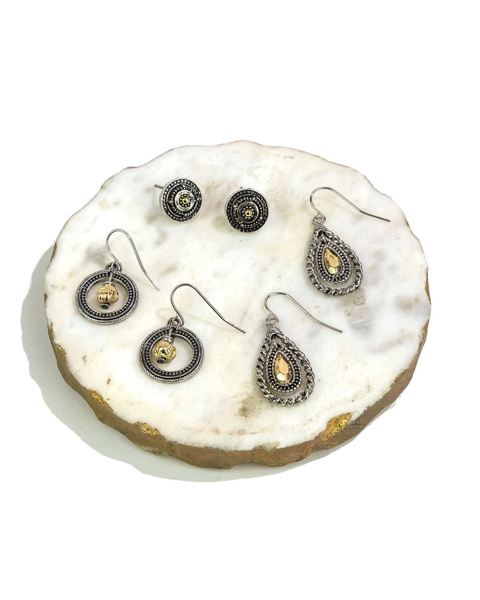 Triple set of silver and gold earrings on a decorative stone surface