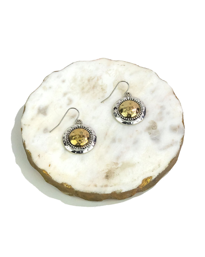 Pair of earrings on a round, white stone surface