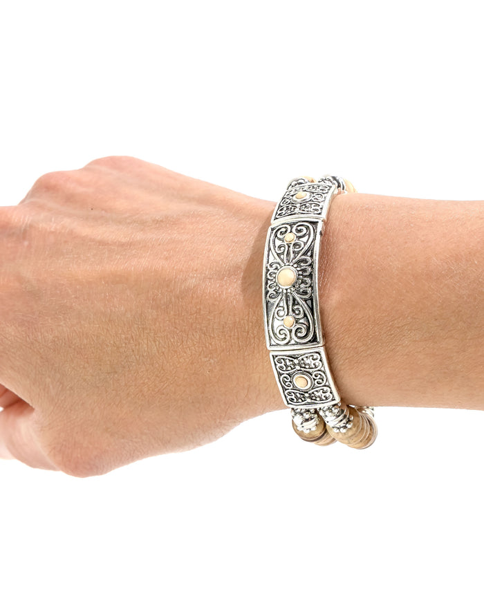 Decorative silver bracelet on a wrist against a white background
