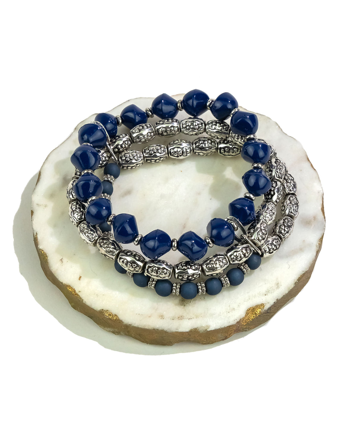 Set of blue beaded bracelets with silver accents on a white stone surface