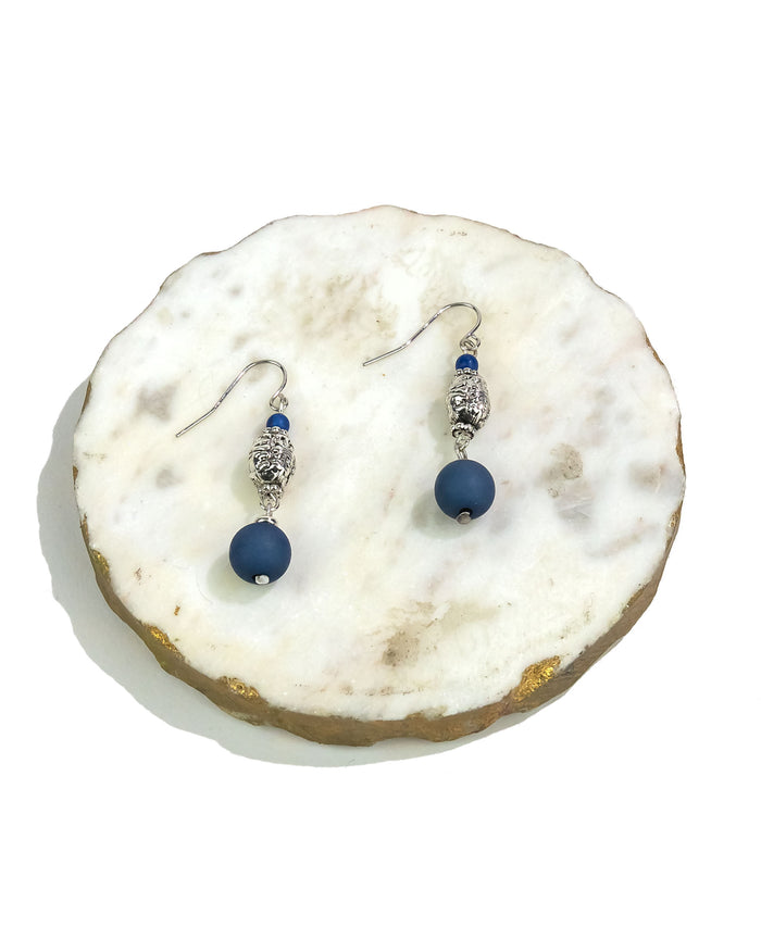Pair of blue beaded earrings on a white stone surface