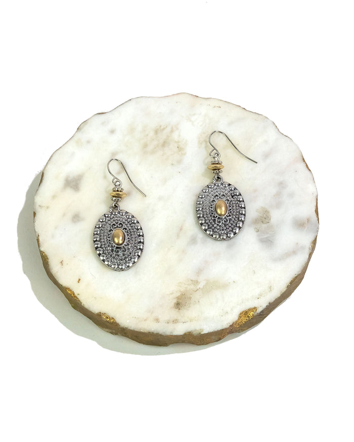 Pair of silver earrings with gold accents on a white stone surface