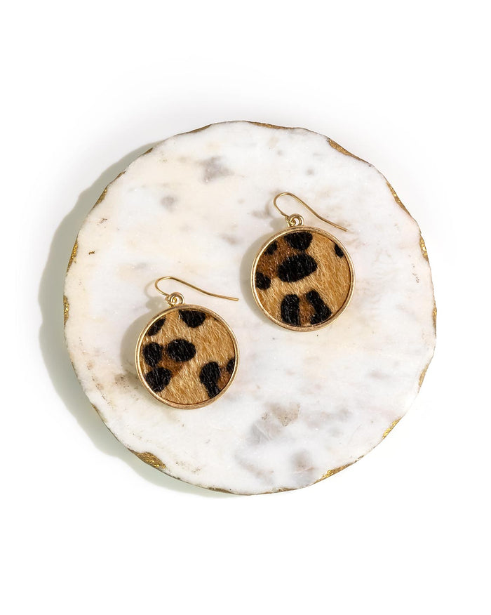 Pair of earrings with leopard print faux fur design on a white marble surface