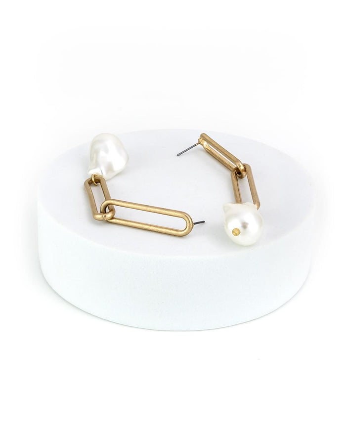 Gold drop earrings with pearl-like beads on a white background