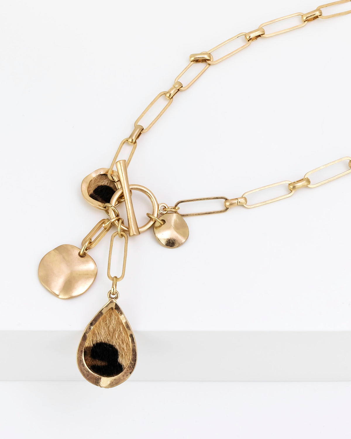 Gold necklace with various charms on a white background