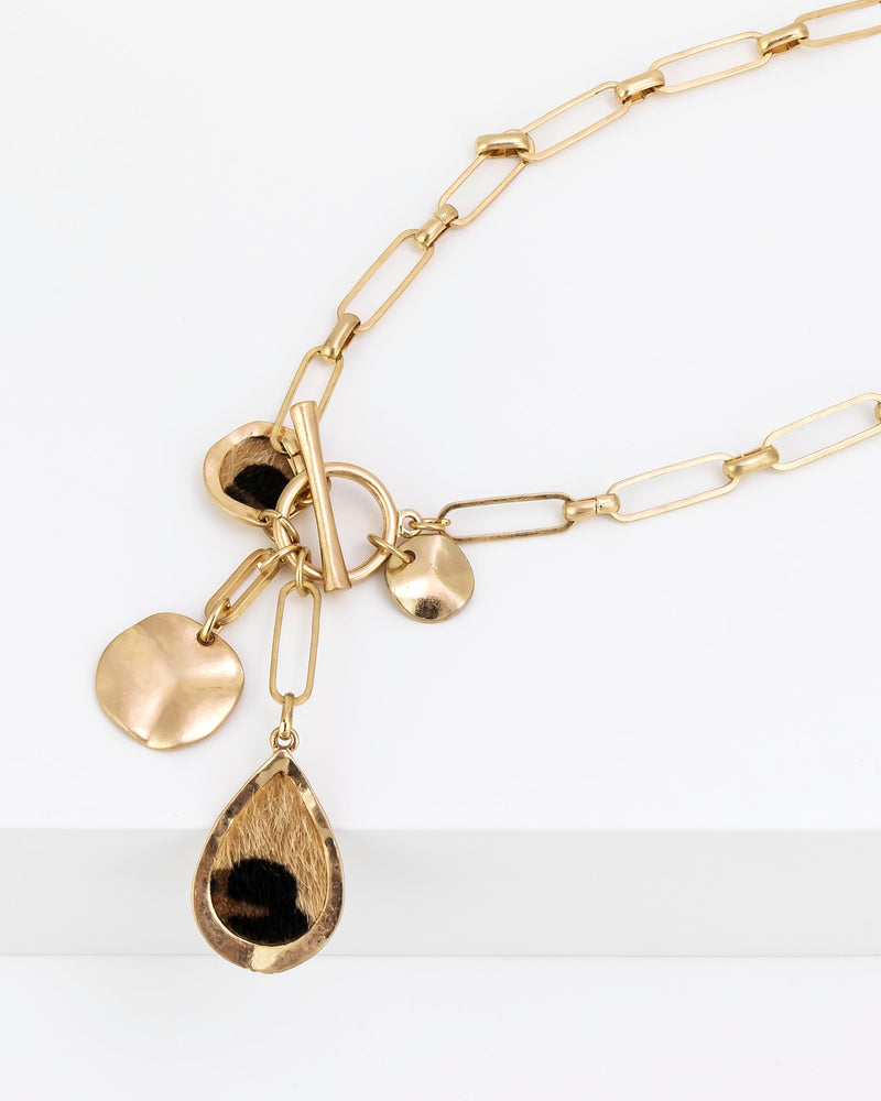 Gold necklace with various charms on a white background