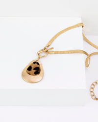 Gold necklace with a teardrop pendant on a white background