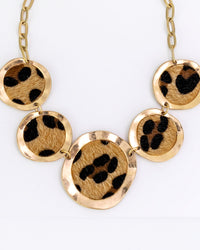 Necklace with gold circular pendants featuring black paw prints on a white background