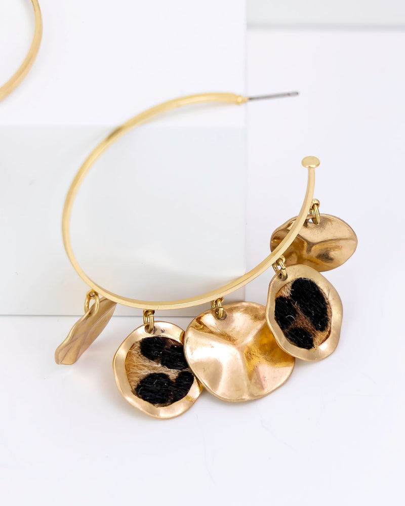 Gold hoop faux fur leopard earrings on a white background