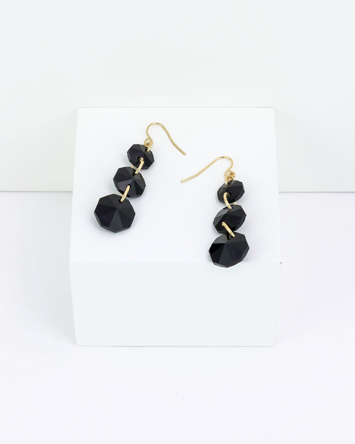 Black faceted three drop earrings on a white background